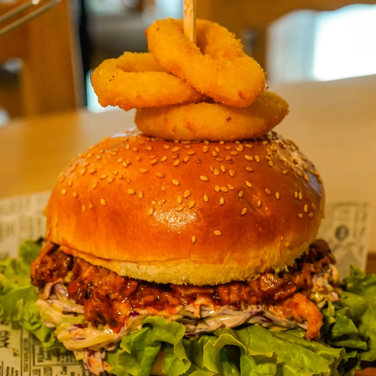 Burger s trganim mesom, solato in čebulnimi obročki.
